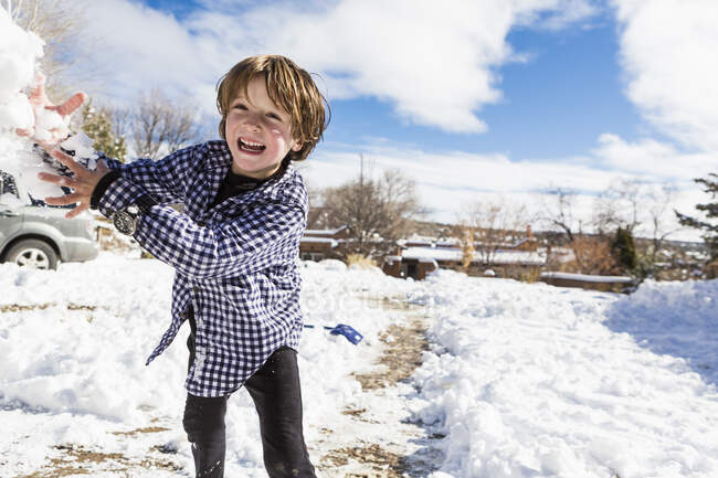 Niño de seis años que lanza una bola de nieve - foto de stock