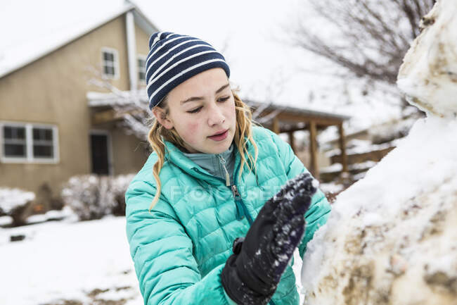 Thirteen year old teenage girl building a snowman — Stock Photo