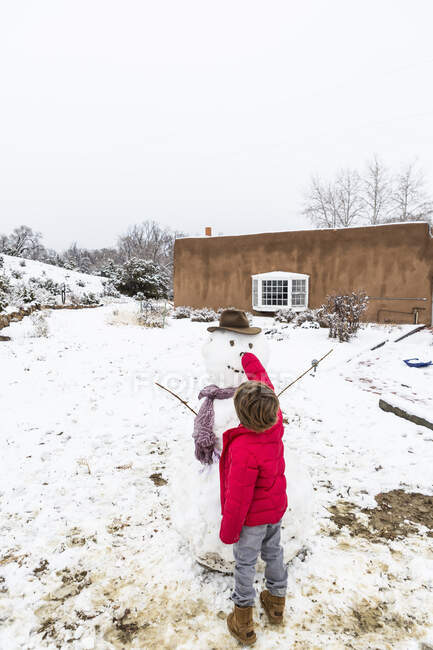 Un niño de seis años que construye un hombre de nieve - foto de stock