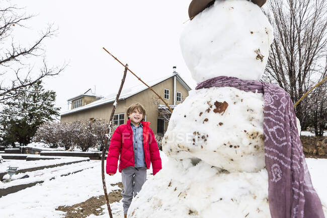 Шестирічний хлопчик будує сніговика — стокове фото
