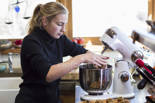 Tredici anni ragazza adolescente utilizzando mixer in cucina. — Foto stock