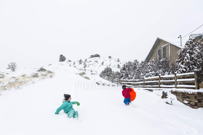 Menino e menina trenó para baixo colina na neve — Fotografia de Stock