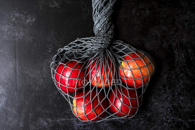 Высокий угол крупным планом красных яблок в серой сетке мешок на черном фоне
. — стоковое фото
