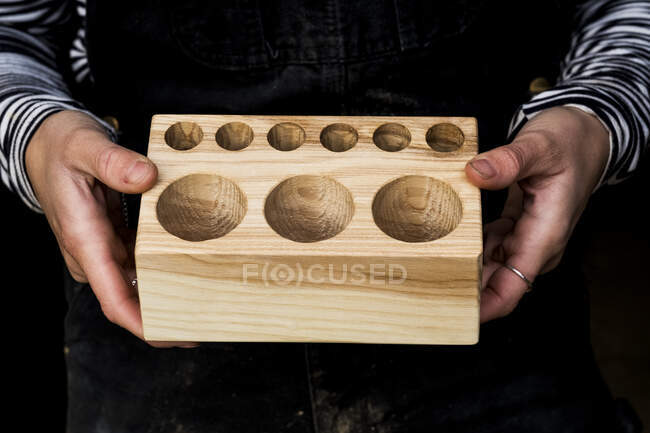 Close up of person holding wooden block with circular holes in different sizes. — Stock Photo