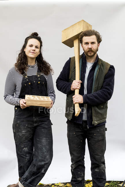 Retrato de mujeres y hombres portadores de bloques de madera de pie delante de fondo blanco, mirando la cámara.. - foto de stock