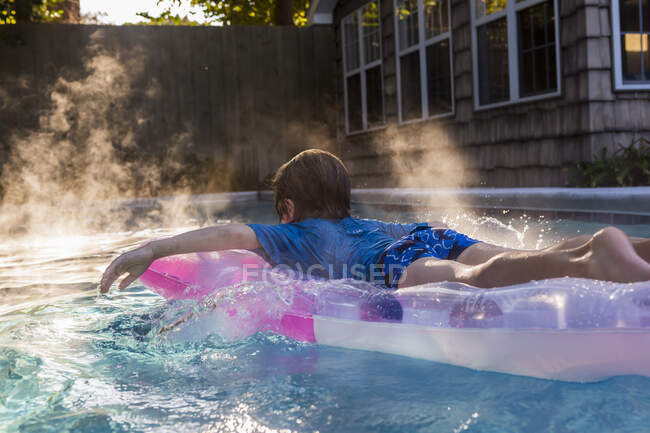 6-летний мальчик играл в бассейне на восходе солнца — стоковое фото