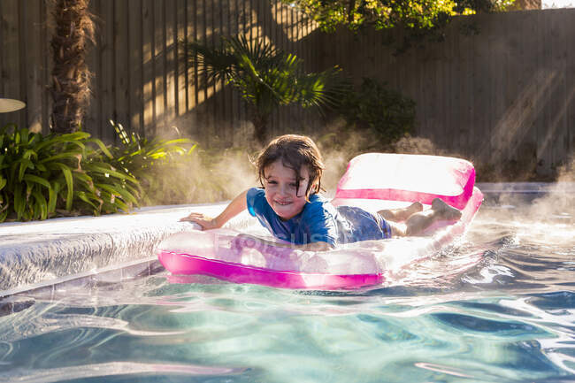 6 year old boy playing in pool at sunrise — Stock Photo
