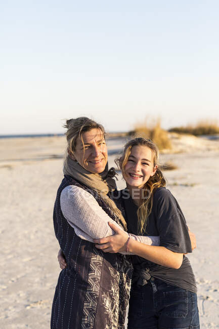 Madre e figlia abbracciate su una spiaggia — Foto stock
