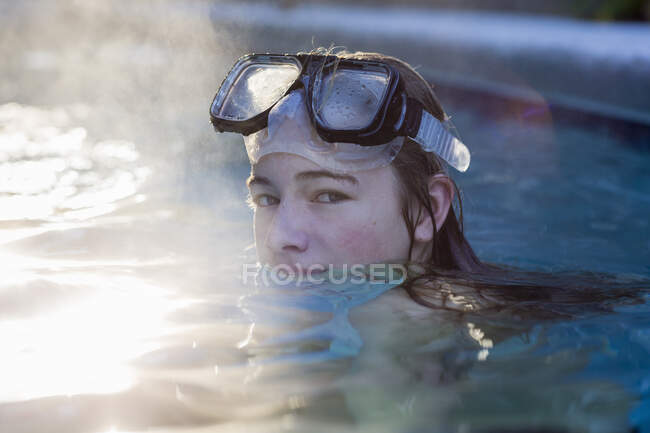 Дівчина-підліток у басейні в окулярах, піднімається пара — стокове фото