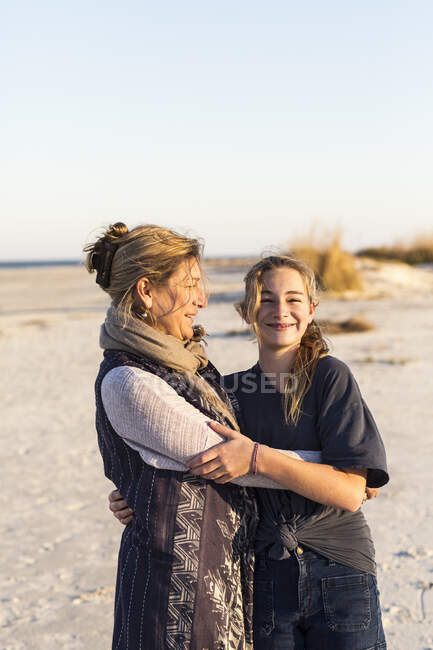 Madre e hija abrazándose en una playa - foto de stock