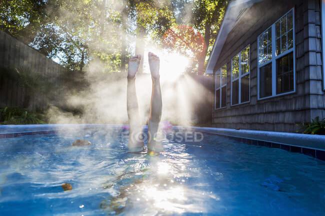 Девочка-подросток плавает в бассейне, ныряет в теплую воду, поднимается пар. — стоковое фото