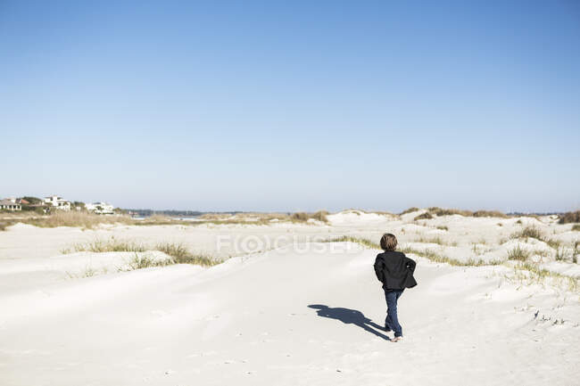Six year old boy walking over sand dunes in open space. — Stock Photo