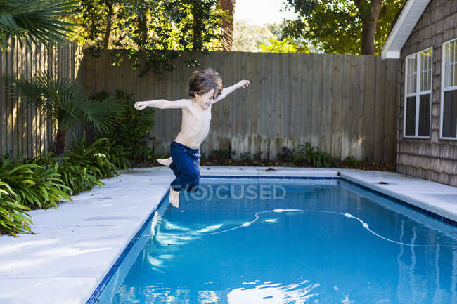 Menino de seis anos saltando para uma piscina — Fotografia de Stock