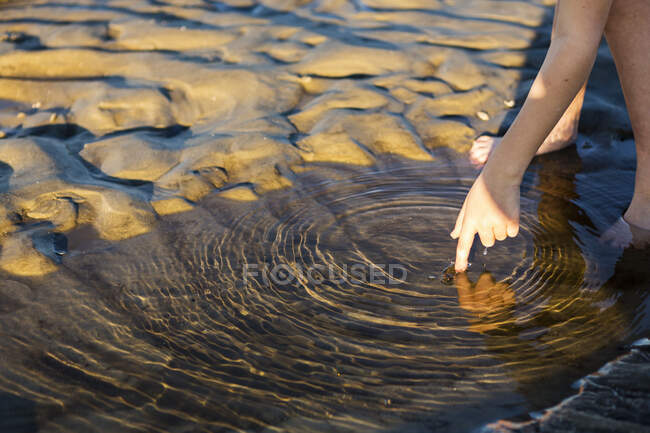 Cerrar el dedo del niño tocando el agua con el dedo - foto de stock