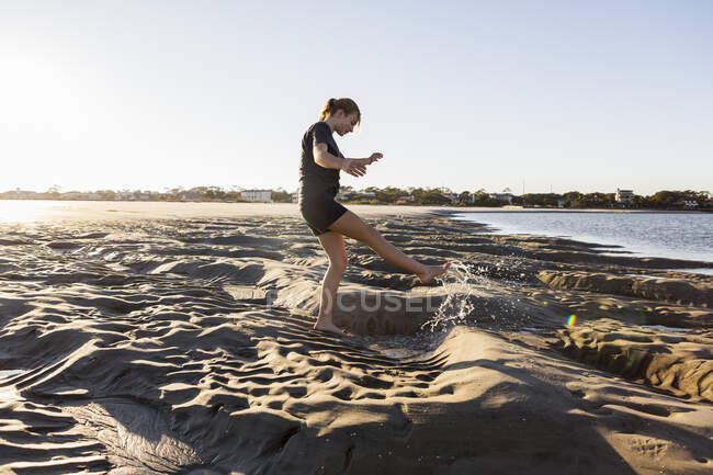 Teenage girl playing in sand dunes, at the beach — Stock Photo