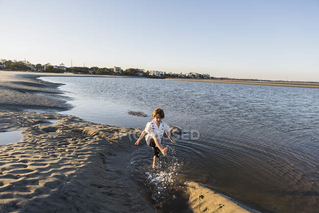 Шестирічний хлопчик на пляжі бризкає в мілководді — стокове фото