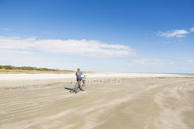 Une adolescente cycliste sur la plage — Photo de stock