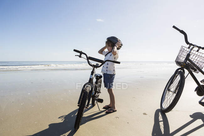 Menino colocando em um capacete ciclo na praia, St. Simon 's Island, Georgia — Fotografia de Stock
