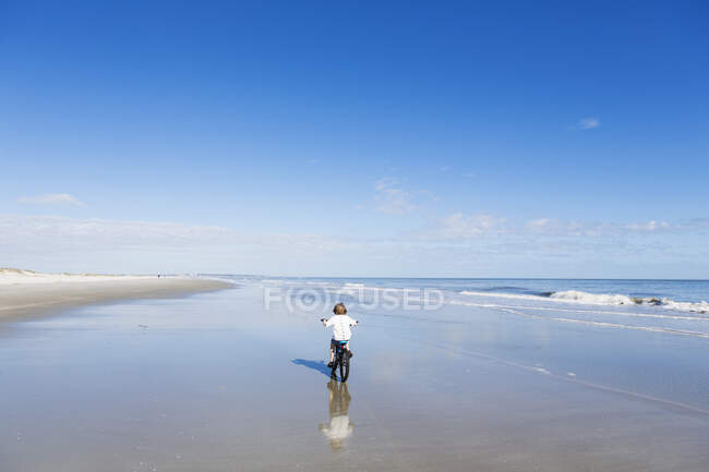 Niño de 6 años en bicicleta en la playa, St. Simon 's Island, Georgia - foto de stock
