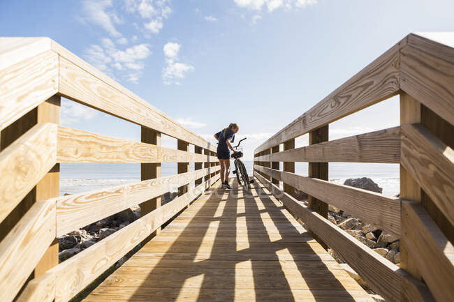 Дівчина-підліток на дерев'яному мосту з її велосипедом — стокове фото