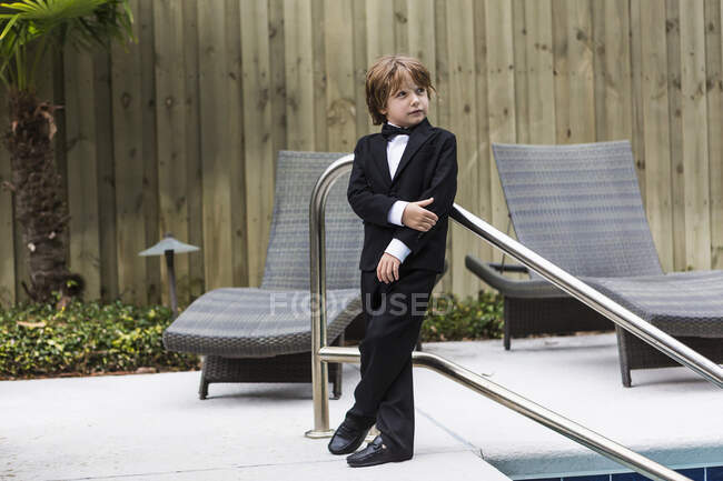 6-річний хлопчик у формальному вбранні, що стоїть біля басейну — стокове фото