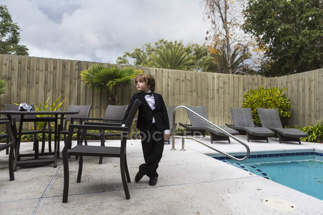 6 year old boy wearing formal attire standing by pool — Stock Photo