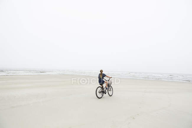 BTT adolescente en la playa de arena junto al océano, Isla de San Simón, Georgia. - foto de stock