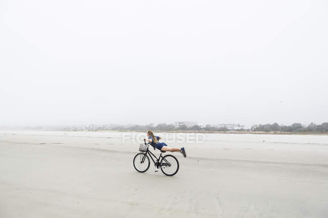 Jeune fille à vélo sur une plage sablonneuse au bord de l'océan, île Saint-Simons, Géorgie — Photo de stock
