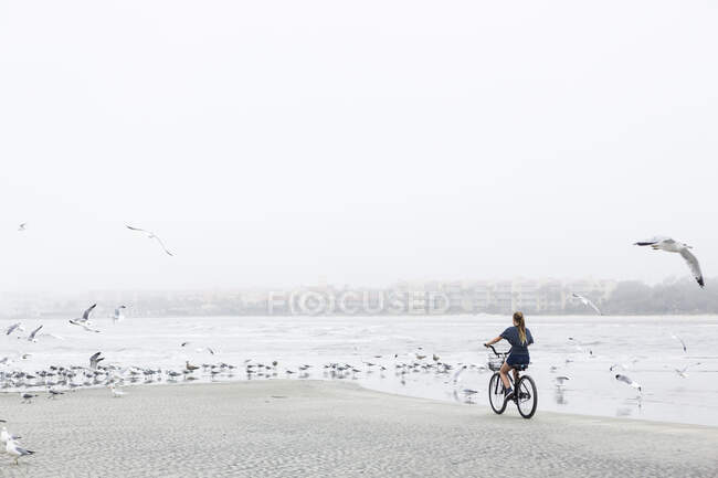 Jeune fille à vélo sur une plage sablonneuse au bord de l'océan, île Saint-Simons, Géorgie — Photo de stock