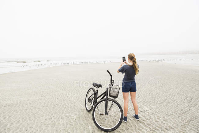 Дівчинка розмовляє фотографіями зі смартфоном на пляжі (острів Святого Симона, Джорджія). — стокове фото