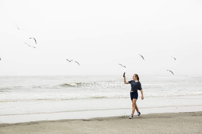Teen girl parlando immagini con smartphone in spiaggia, St. Simon Island, Georgia — Foto stock