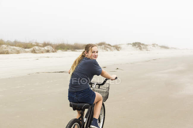 Teen girl in bicicletta sulla sabbia in spiaggia, St. Simons Island, Georgia — Foto stock