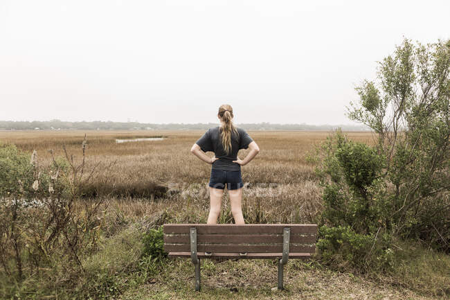 Teenage girl standing on a bench looking out over marshes, St. Simon's Island, Georgia — Stock Photo