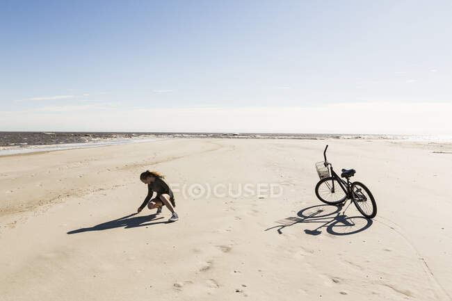 Adolescente menina em um largo vazio praia coletando conchas. — Fotografia de Stock