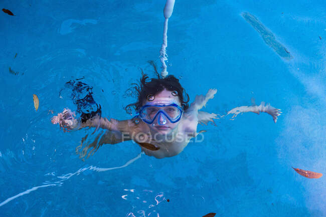 Junge schwimmt mit Brille unter Wasser im Pool. — Stockfoto