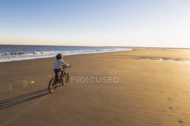 Niño de 6 años que monta una bicicleta en la playa, St. La isla de Simon, Georgia - foto de stock