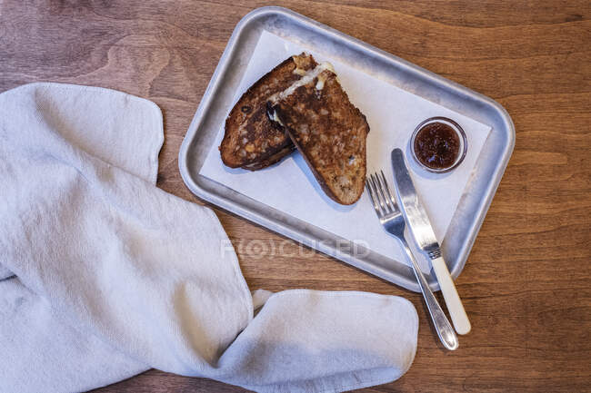 Gran ángulo de cierre de rebanadas tostadas de pan, mermelada y cubiertos en bandeja en una panadería artesanal . - foto de stock