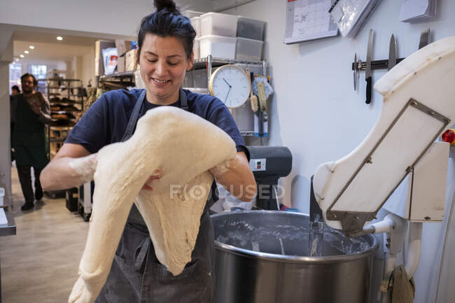 Жінка в фартусі стоїть в хлібобулочних виробах, працює з кислинкою . — стокове фото