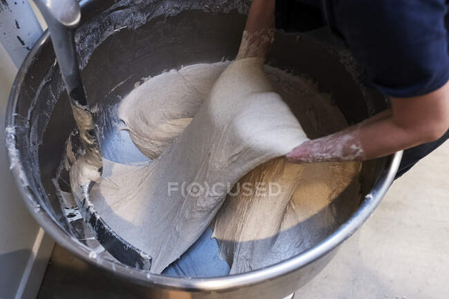 Alto angolo da vicino di persona che prepara pasta madre in un mixer industriale in una panetteria artigianale . — Foto stock