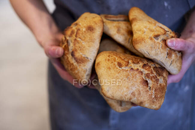 Großaufnahme einer Person mit frisch gebackenen Brötchen in einer handwerklichen Bäckerei. — Stockfoto