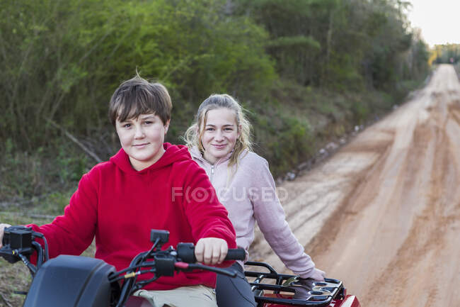Двое подростков едут на коляске, вся местность на грязной трассе. — стоковое фото