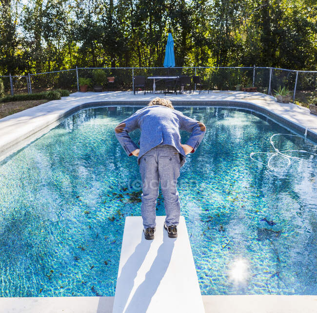 6 anno vecchio ragazzo standing su diving board con vista piscina — Foto stock