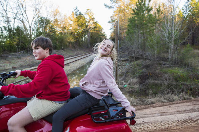 Two teenagers riding on a buggy, all terrain vehicle on a muddy track. — Stock Photo