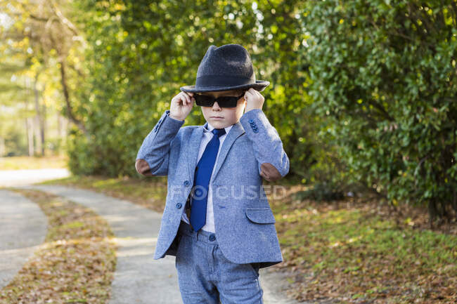 Menino de 6 anos vestido de terno e vestindo fedora, na entrada de carro — Fotografia de Stock