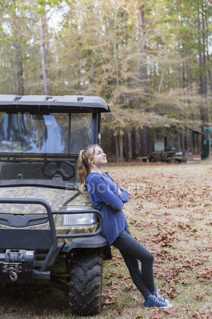 A teenage girl by an all terrain vehicle, a buggy, leaning with arms folded. — Stock Photo