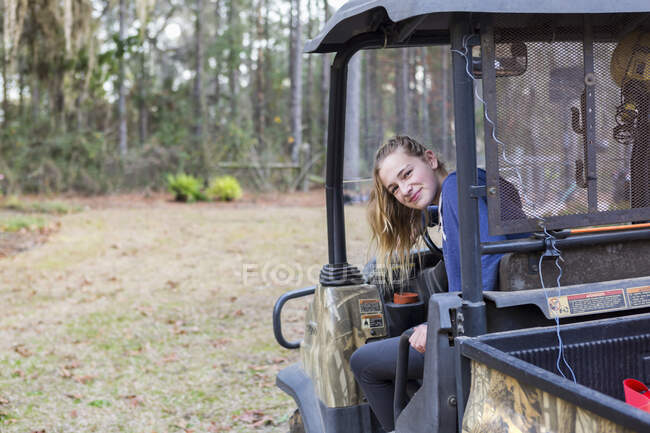 Una adolescente en un vehículo todo terreno, un buggy, mirando hacia fuera . - foto de stock