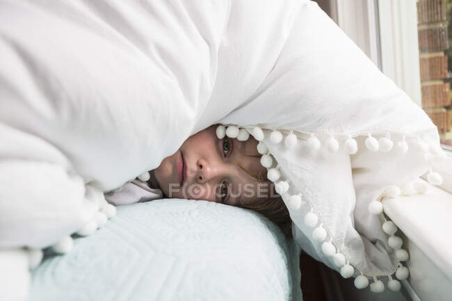 Garçon de 6 ans au lit avec couverture au-dessus de sa tête — Photo de stock