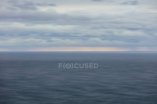 Movimento turvo abstrato do oceano, horizonte e céu tempestuoso ao entardecer — Fotografia de Stock