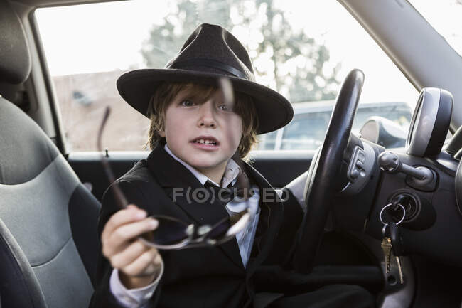 6 year old boy sitting in car holding steering wheel — Stock Photo