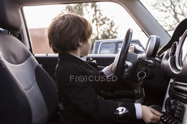 6 year old boy sitting in car holding steering wheel — Stock Photo